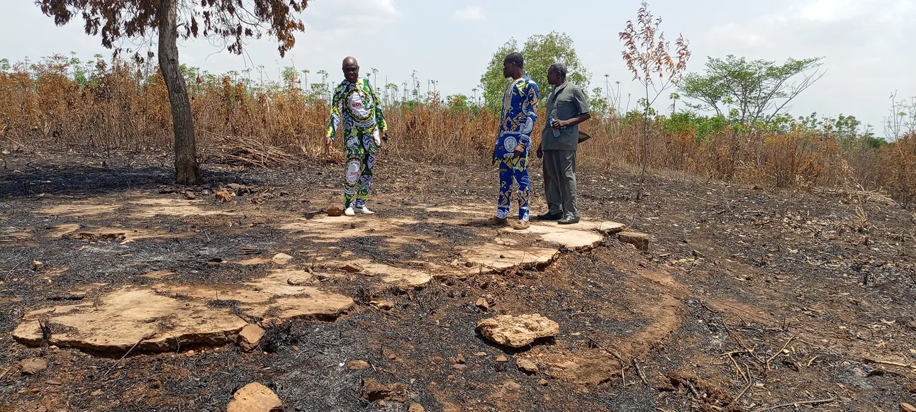 Le maire montrant le reste du cimentage du sol de la paillotte sous laquelle se reposait  le président Hubert Koutoukou Maga, père de l’Indépendance du Bénin
